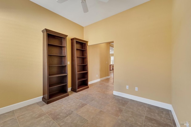 tiled empty room with baseboards and ceiling fan