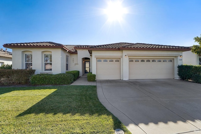 mediterranean / spanish-style house with a garage, driveway, a front lawn, and stucco siding