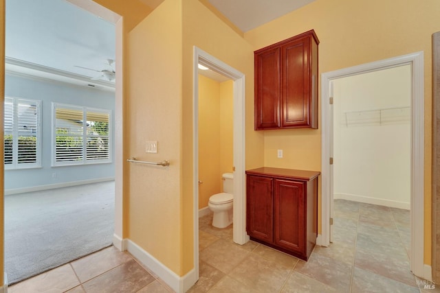 bathroom featuring toilet, tile patterned flooring, baseboards, and a ceiling fan