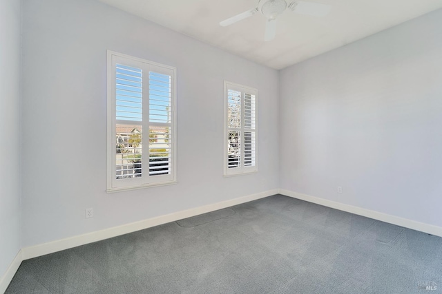 empty room with dark colored carpet, ceiling fan, and baseboards