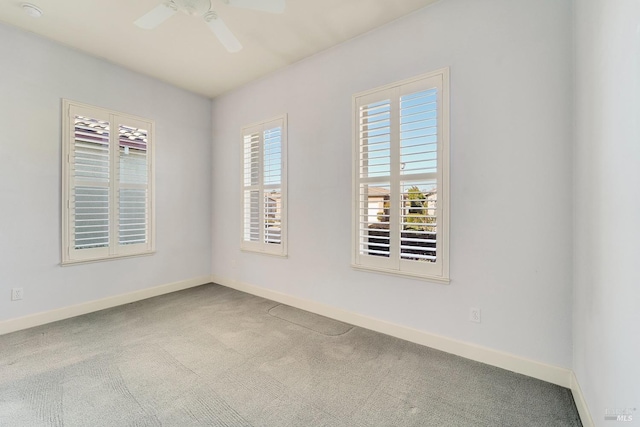 carpeted empty room featuring ceiling fan and baseboards