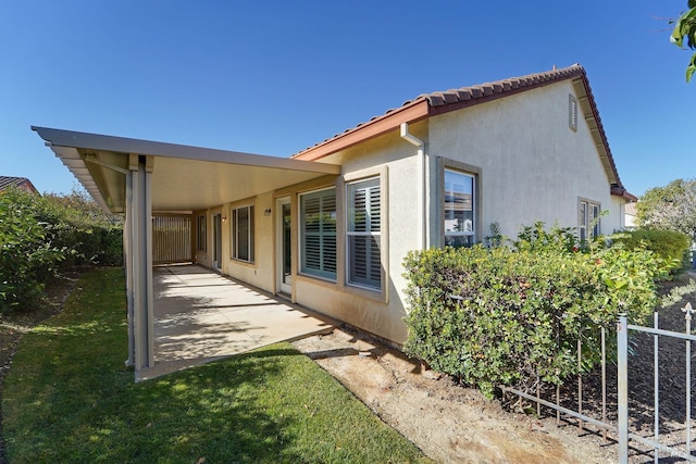 view of side of home featuring stucco siding and fence