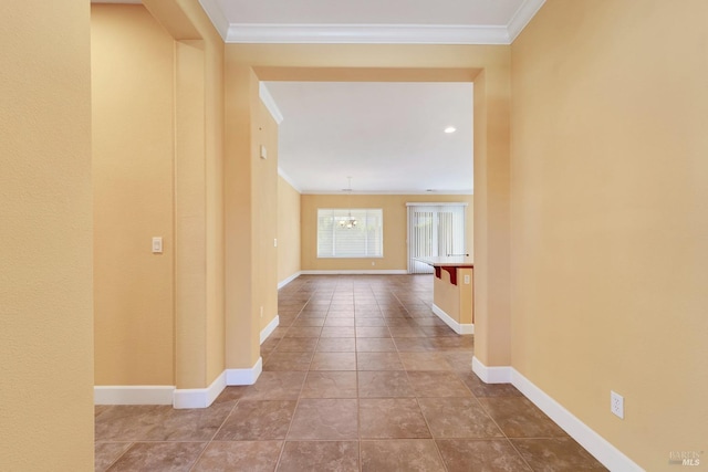 hall featuring a chandelier, tile patterned flooring, crown molding, and baseboards