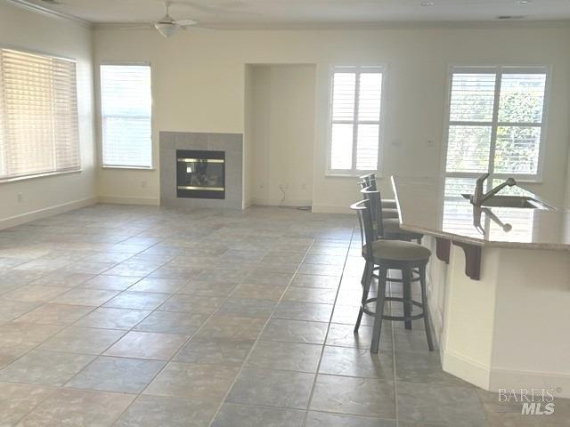 living area featuring crown molding, ceiling fan, and baseboards