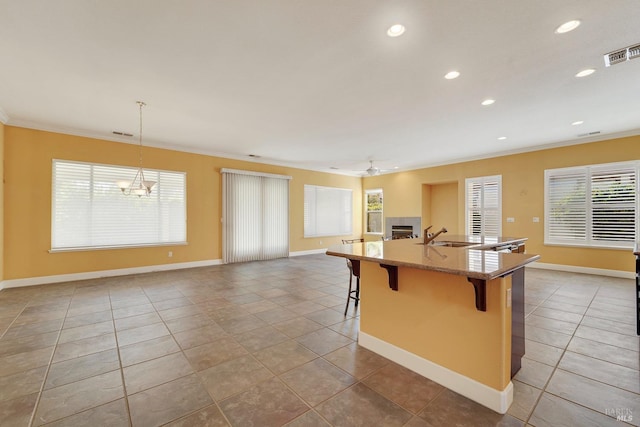 kitchen featuring a fireplace, a breakfast bar area, visible vents, ornamental molding, and ceiling fan with notable chandelier