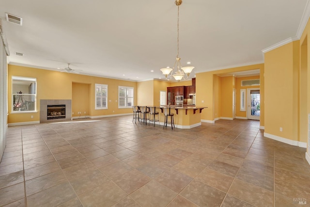 living room featuring plenty of natural light, visible vents, crown molding, and ceiling fan with notable chandelier