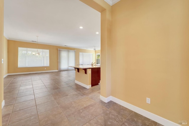 empty room featuring baseboards, ornamental molding, a chandelier, and a wealth of natural light
