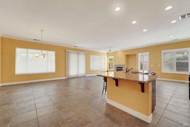 kitchen featuring visible vents, a fireplace, tile patterned floors, ornamental molding, and a breakfast bar