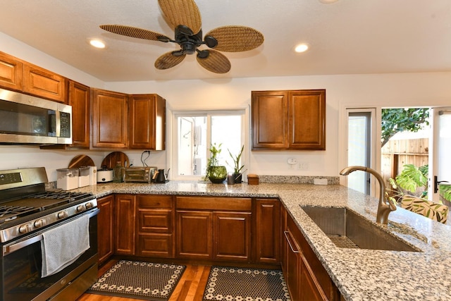 kitchen featuring stainless steel appliances, light stone counters, a sink, and light wood-style flooring