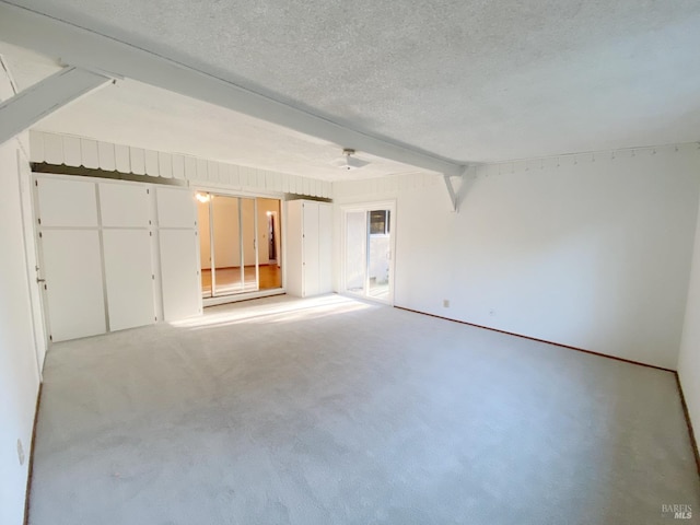 spare room with beam ceiling, light colored carpet, and a textured ceiling