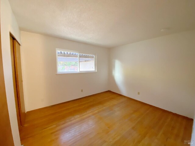 spare room featuring hardwood / wood-style floors and a textured ceiling