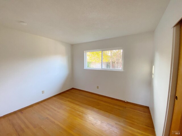 empty room featuring light hardwood / wood-style flooring and a textured ceiling