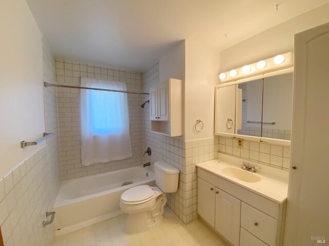 full bathroom with tiled shower / bath, vanity, toilet, and tile walls