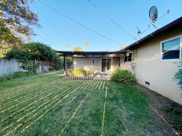 rear view of house featuring stucco siding, fence, a lawn, and crawl space