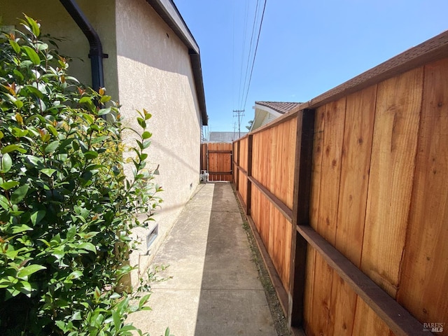 view of side of home with stucco siding and fence
