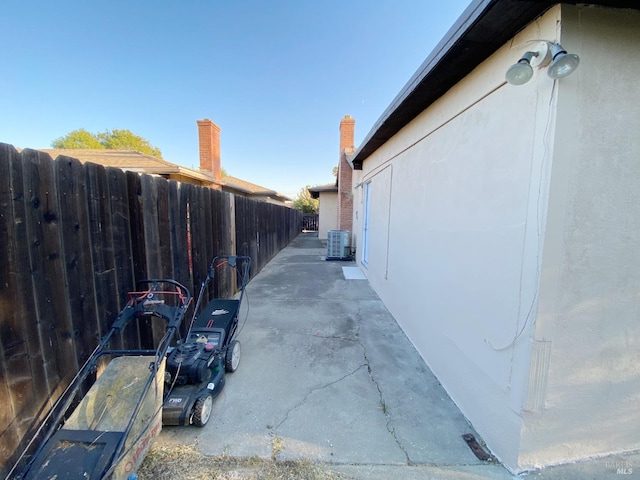 view of home's exterior with central air condition unit, a patio, and fence
