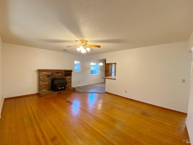 unfurnished living room with ceiling fan, a textured ceiling, and light wood-type flooring