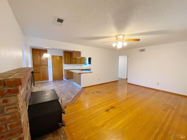 unfurnished living room featuring ceiling fan, a textured ceiling, and light wood-type flooring