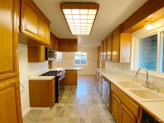 kitchen with stainless steel appliances, hanging light fixtures, sink, and kitchen peninsula