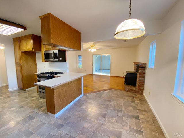 kitchen with appliances with stainless steel finishes, decorative light fixtures, ceiling fan, kitchen peninsula, and a healthy amount of sunlight