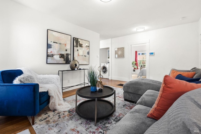 living room with hardwood / wood-style flooring, washer / clothes dryer, and a baseboard radiator