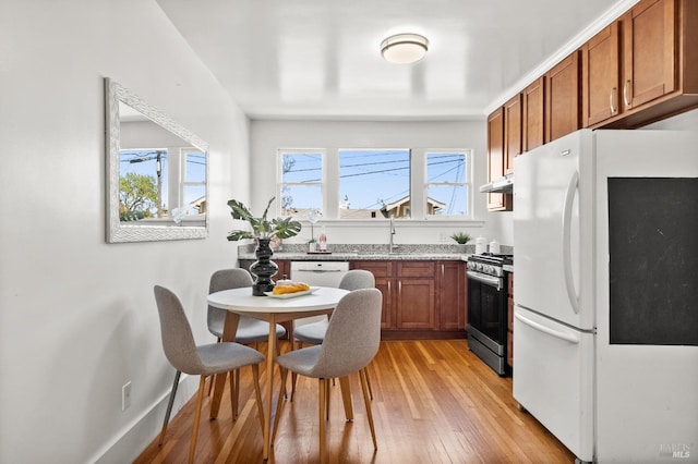 kitchen with white refrigerator, light wood-type flooring, sink, and stainless steel gas range