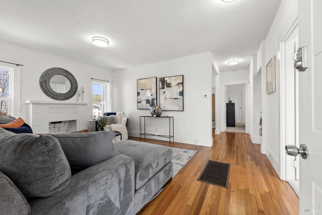 living room with a brick fireplace and light hardwood / wood-style flooring