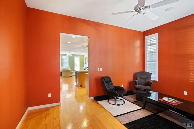 living area featuring wood-type flooring and ceiling fan