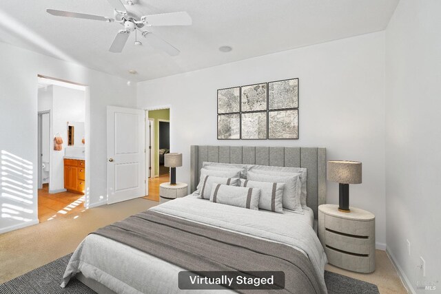 bedroom featuring light colored carpet, ensuite bath, baseboards, and ceiling fan