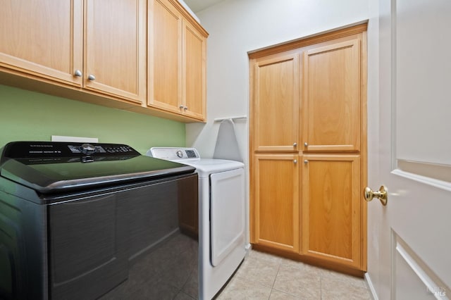 laundry area featuring washer and dryer, cabinet space, and light tile patterned floors