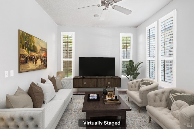 living room with a ceiling fan and a textured ceiling