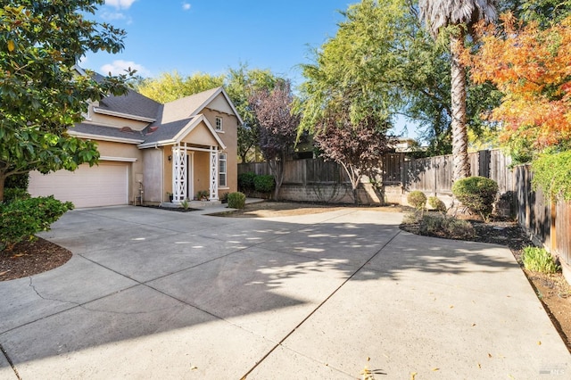view of front facade featuring driveway, stucco siding, fence, a garage, and a shingled roof