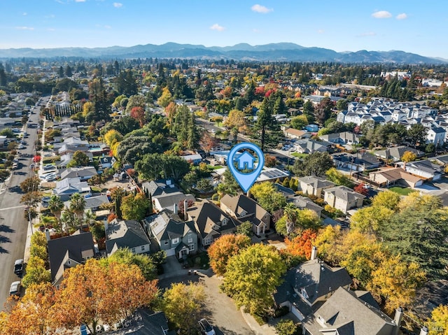 aerial view of property and surrounding area featuring a mountainous background and nearby suburban area