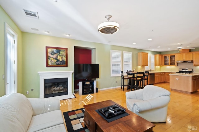 living room with light hardwood / wood-style flooring and ceiling fan