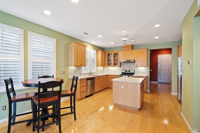 kitchen featuring appliances with stainless steel finishes, under cabinet range hood, a center island, light countertops, and ceiling fan