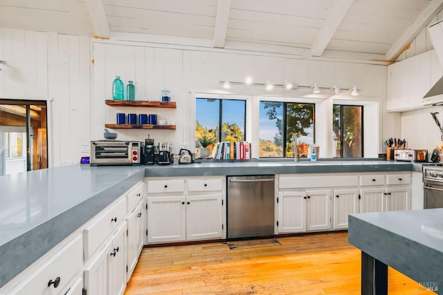 kitchen featuring white cabinetry, a wealth of natural light, wooden walls, and light hardwood / wood-style floors