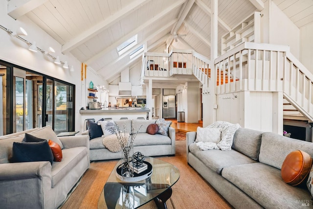 living room featuring high vaulted ceiling, beamed ceiling, and light hardwood / wood-style flooring