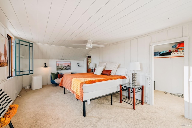 carpeted bedroom featuring wooden walls, ceiling fan, and vaulted ceiling