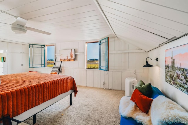 carpeted bedroom with wooden walls, ceiling fan, and vaulted ceiling