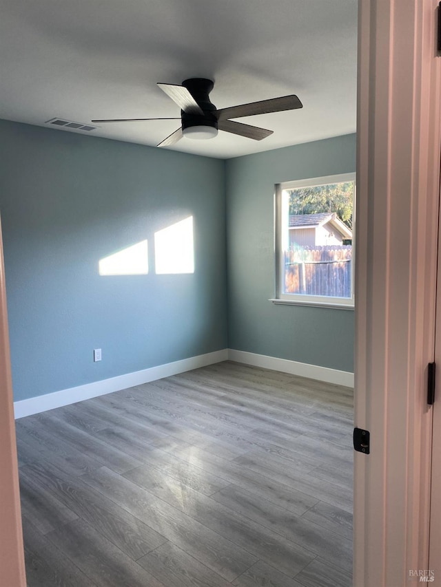 empty room featuring baseboards, ceiling fan, dark wood-style floors, and visible vents