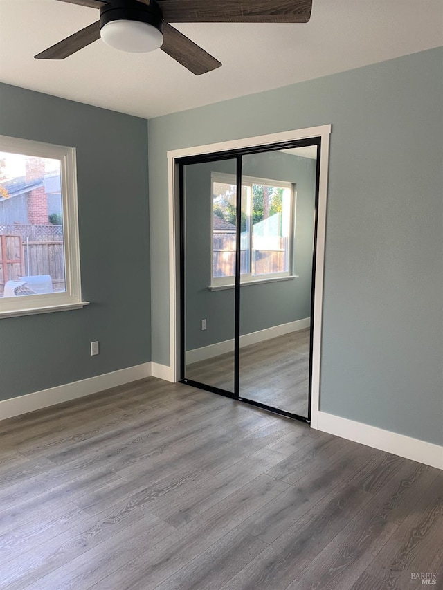 unfurnished bedroom with baseboards, a ceiling fan, a closet, and wood finished floors