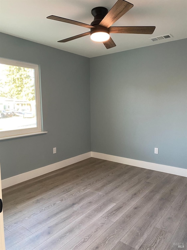 unfurnished room featuring visible vents, baseboards, ceiling fan, and dark wood-style floors