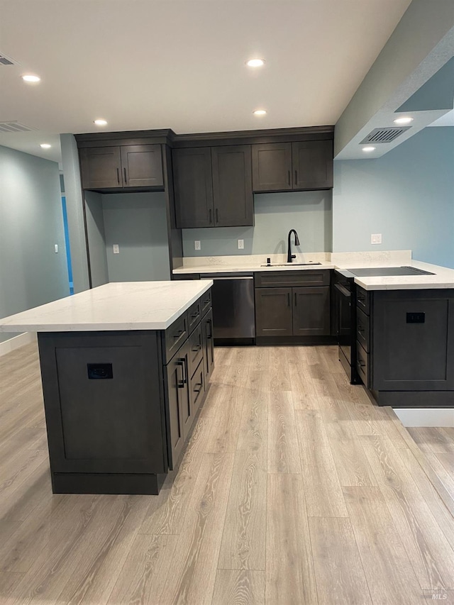 kitchen with a sink, light wood-style floors, stainless steel dishwasher, and visible vents
