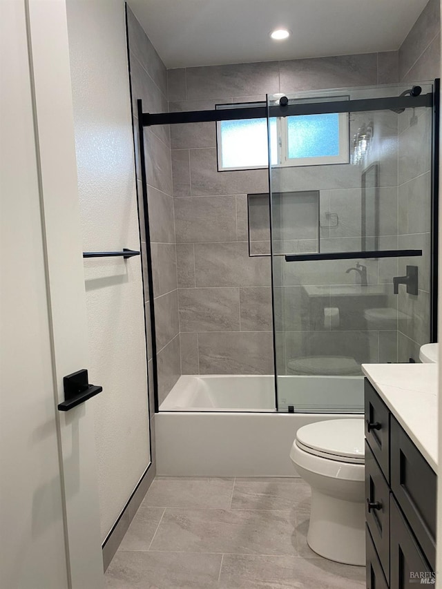 bathroom featuring vanity, combined bath / shower with glass door, and toilet