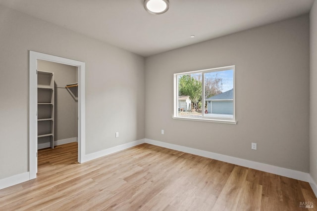 unfurnished bedroom featuring a closet, a walk in closet, and light hardwood / wood-style flooring