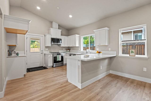 kitchen featuring kitchen peninsula, appliances with stainless steel finishes, a healthy amount of sunlight, and white cabinets