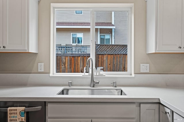 kitchen with dishwasher, white cabinetry, and sink