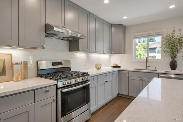 kitchen featuring sink, light stone counters, appliances with stainless steel finishes, dark wood-type flooring, and gray cabinetry