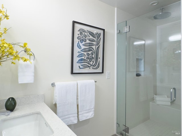 bathroom featuring a shower with shower door and vanity