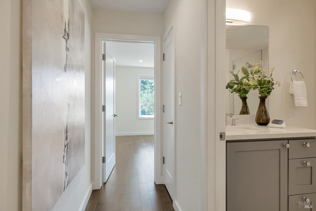 corridor with dark hardwood / wood-style floors and sink